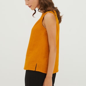 May include: A sleeveless, mustard yellow linen top with a round neckline and a side slit. The top is made of a lightweight, breathable fabric and is perfect for warm weather.