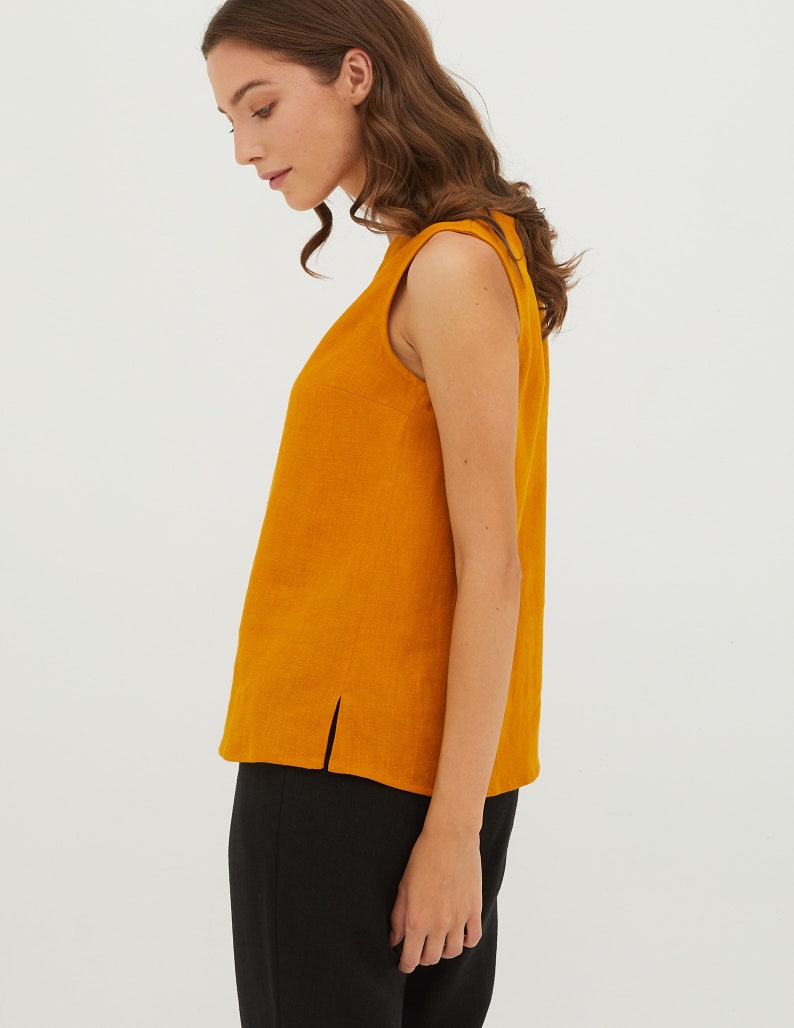 May include: A sleeveless, mustard yellow linen top with a round neckline and a side slit. The top is made of a lightweight, breathable fabric and is perfect for warm weather.