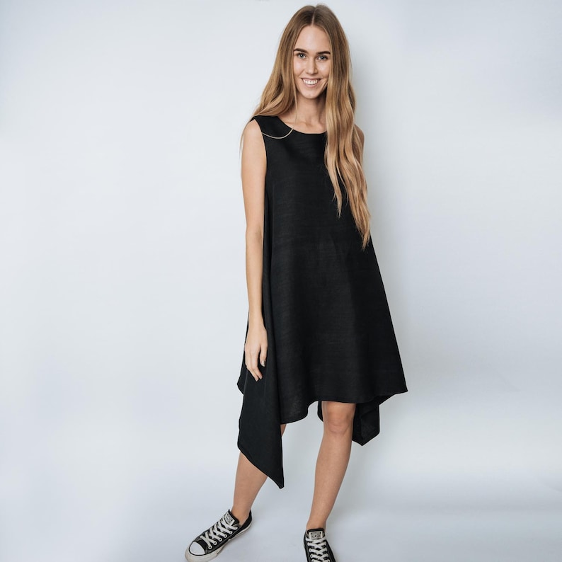 May include: A black sleeveless dress with a high neckline and an asymmetrical hemline. The dress is made of a lightweight fabric and has a relaxed fit.