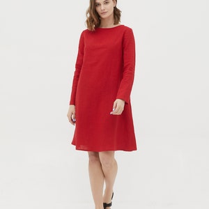 May include: A red linen dress with long sleeves and a boat neck. The dress has a slightly flared skirt and is knee-length.