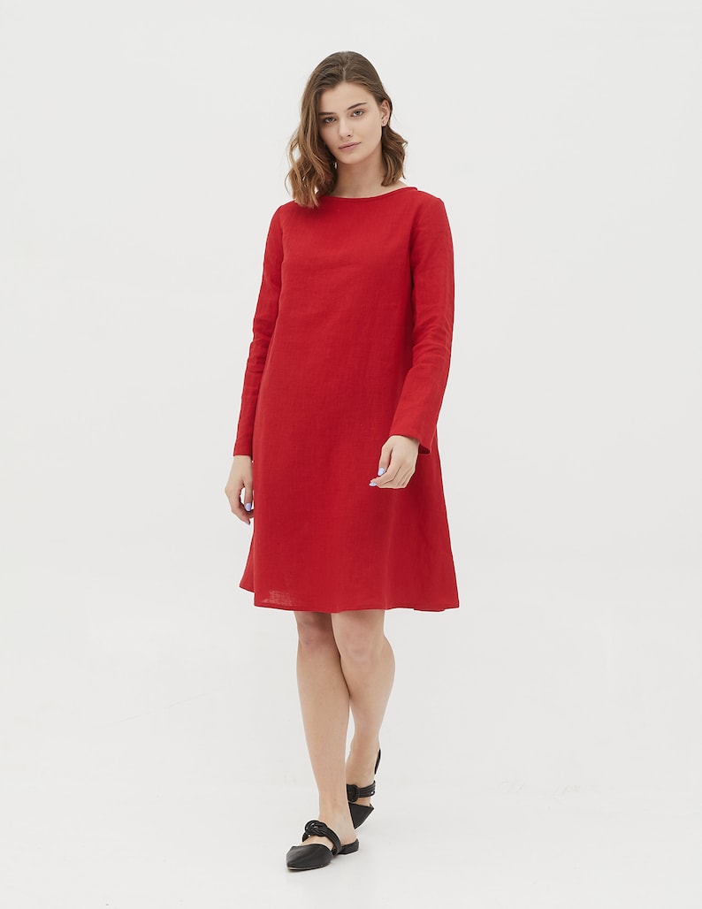 May include: A red linen dress with long sleeves and a boat neck. The dress has a slightly flared skirt and is knee-length.