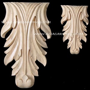 May include: Two wooden corbels with intricate leaf carvings. The corbels are unfinished and have a natural wood colour. The larger corbel is approximately 30 cm tall and the smaller corbel is approximately 15 cm tall.