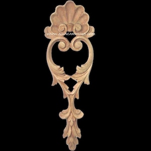 May include: A carved wooden decorative architectural element. The design features a shell-like top, a heart-shaped central element with scroll details, and a stylized leaf base. The wood has a natural, light brown color.