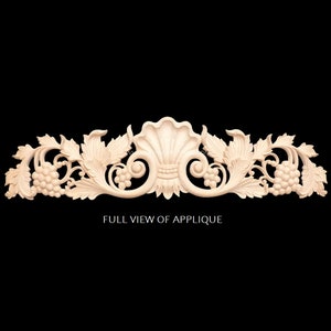 May include: A carved wooden applique with a shell design and grapevine accents. The applique is made of light wood and has a natural finish. It is a decorative element that can be used to add detail to furniture, doors, or walls.