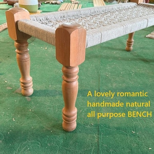 Puede incluir: Banco de madera con asiento tejido y cuatro patas torneadas. El banco tiene un acabado de madera natural y lleva la inscripción "A lovely romantic handmade natural all purpose BENCH".