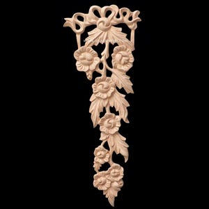 May include: A carved wooden floral applique featuring roses and leaves. The natural wood piece has a decorative bow at the top and the website www.asiacarvings.com is visible. This decorative element is suitable for furniture or craft projects.