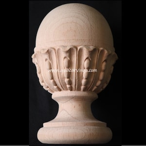May include: A wooden finial with a round top and a decorative base. The finial is made of light wood and has a smooth finish. The base of the finial is decorated with a carved design.