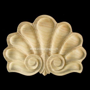 May include: A wooden decorative carving in the shape of a scallop shell with intricate details. The carving is light brown in color and has a smooth finish.