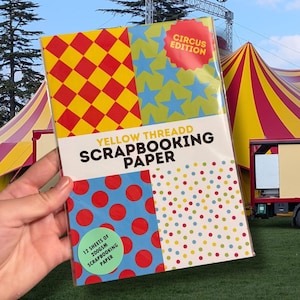 Könnte beinhalten: Eine Packung Yellow Threadd Scrapbooking-Papier in einer transparenten Kunststoffhülle. Das Cover zeigt vier Quadranten mit roten und gelben Rauten, blauen Sternen auf Grün, roten Punkten auf Blau und bunten Punkten auf weißem Hintergrund.