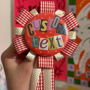 May include: A custom text button with red and white checkered ribbon accents and a cream polka dot ribbon. The button has the words "CUSTOM TEXT" in a colorful, collage-style font. A decorative accessory.