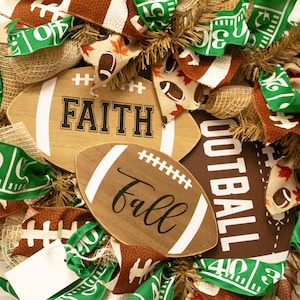 Op de afbeelding: Een bruine en groene voetbal-krans met jute, linten en twee houten voetbalborden met de tekst "FAITH" en "fall".