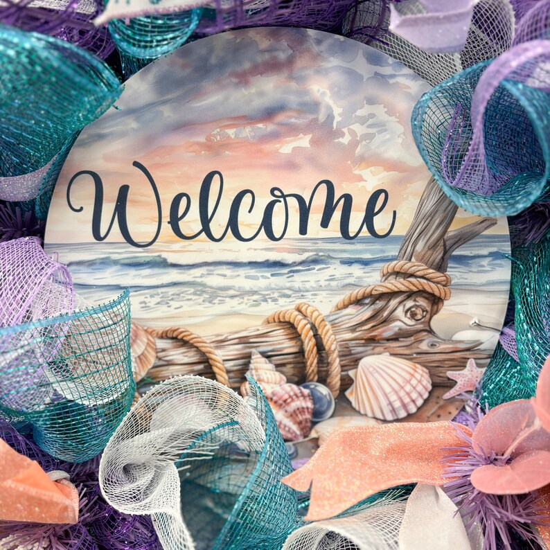 May include: A round wreath with a beach-themed design. The center features a watercolor painting of a beach scene with the word "Welcome". The wreath is decorated with seashells, driftwood, and teal, purple, and coral ribbons.