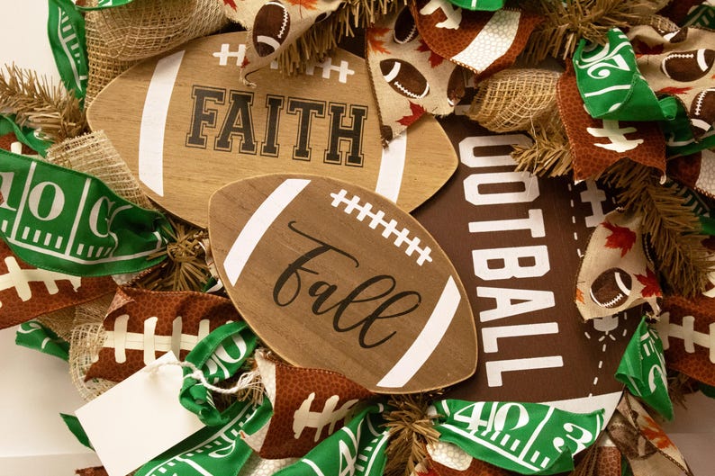 Op de afbeelding: Een bruine en groene voetbal-krans met jute, linten en houten borden met de tekst "Faith" en "Fall".