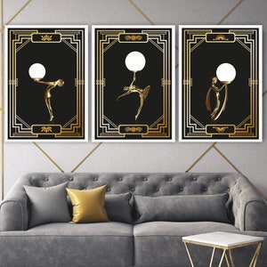 K&ouml;nnte beinhalten: Drei goldene gerahmte Kunstdrucke mit schwarzen Hintergr&uuml;nden und goldenen Silhouetten von Figuren, die Gl&uuml;hbirnen halten. Die Rahmen haben ein geometrisches Design.
