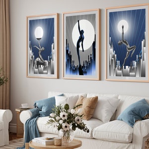 May include: Three framed art prints with a blue and silver color scheme. Each print features a stylized silhouette of a woman in a city setting with a large moon in the background.