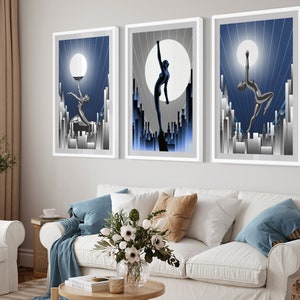 May include: Three framed art prints with a blue and silver color scheme. Each print features a stylized silhouette of a woman dancing against a backdrop of a city skyline and a large moon.