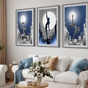 May include: Three framed art prints with a blue and silver color scheme. Each print features a stylized silhouette of a woman dancing against a backdrop of a city skyline and a large moon.