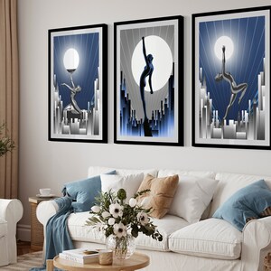 May include: Three framed art prints with a blue and silver color scheme. Each print features a stylized silhouette of a person dancing against a backdrop of a city skyline and a large moon.