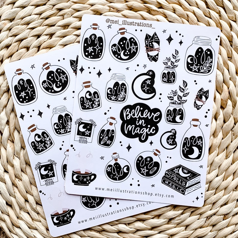 May include: Two sticker sheets featuring black and white illustrations of potion bottles, crystals, moons, stars, and the phrase "Believe in Magic." Additional elements include a teacup and a spell book. The stickers are on a white background.