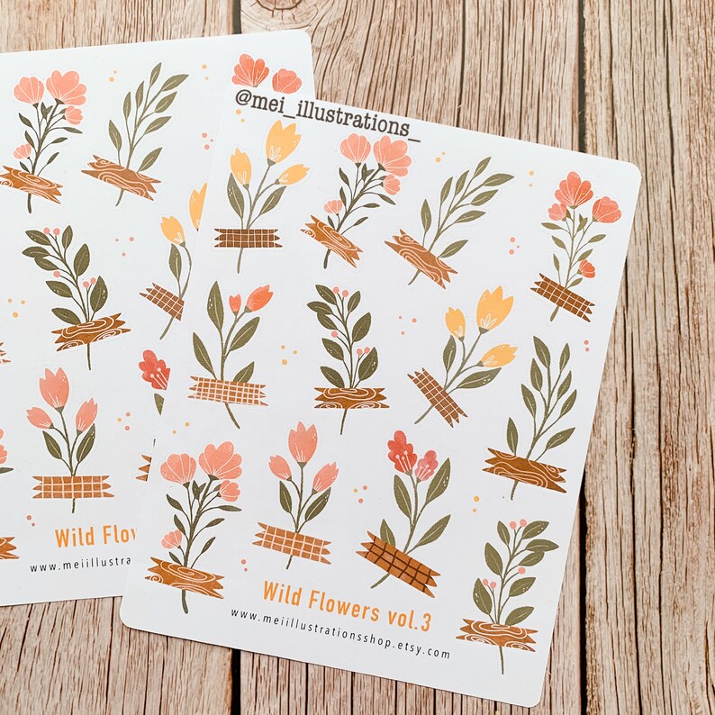 May include: Two sticker sheets featuring floral illustrations in peach, orange, and green. The flowers are secured with brown tape. The text "Wild Flowers vol. 3" and a website address are printed on the stickers.