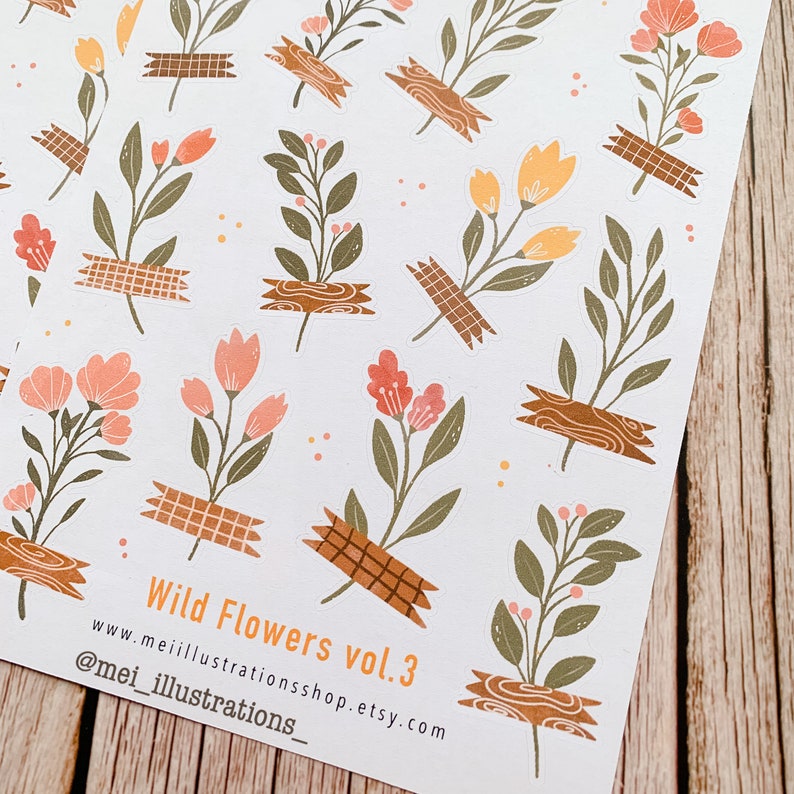 May include: Sheets of stickers featuring floral illustrations. The stickers showcase various wildflowers in shades of peach, orange, and green, secured with decorative tape. The text "Wild Flowers vol.3" is visible.