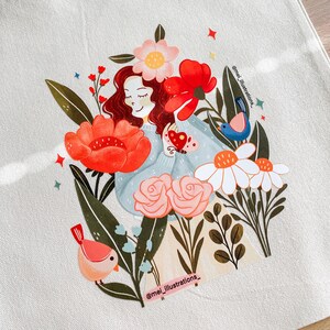 May include: Illustration of a woman with red hair, wearing a light blue sweater, surrounded by red, pink, and white flowers and birds. The birds are pink and blue. The text "@mei_illustrations_" is visible.
