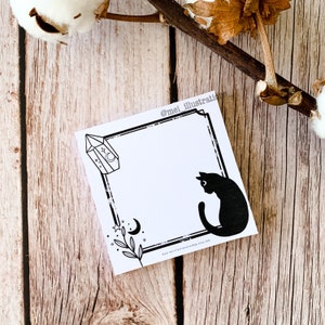 Könnte beinhalten: Quadratischer weißer Notizblock mit schwarzem Rand und Illustrationen. Mit einer schwarzen Katze, einem Kristall, einem Mond und botanischen Elementen. Der Text "@mei_illustrations" und "www.meiillustrationshop.etsy.com" sind ebenfalls sichtbar.