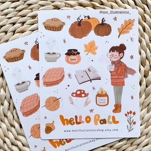 May include: Two sticker sheets with fall-themed illustrations. The designs include pumpkins, pie, jam, a person drinking from a mug, and the text "hello fall". The stickers are in shades of orange, brown, and beige.
