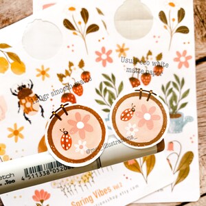 May include: A collection of stickers with a spring theme. The stickers feature floral designs, ladybugs, and the text "Spring Vibes Vol. 2". The stickers are printed on 120gr smooth matte and usual eco white matte paper.