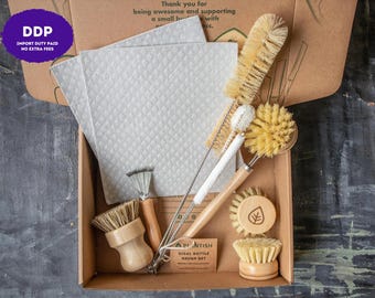 May include: A cleaning kit in a cardboard box containing two light gray textured cloths, a long-handled sisal bottle brush, a thin wire brush, a round wooden dish brush with a leaf icon, a small wooden scrub brush, and a small metal scraper.