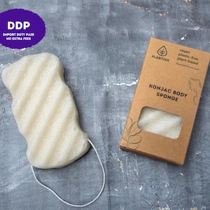 May include: A beige, wavy-textured konjac body sponge with a white hanging string, positioned next to its rectangular brown cardboard packaging. The box features the text Plantish, vegan, plastic-free, plant-based, and Konjac Body Sponge.