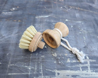 May include: A wooden brush with natural bristles and a wooden handle with a string attached. The brush is separated from the handle.