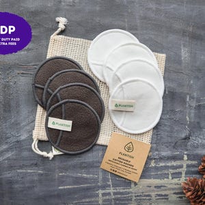 Peut inclure: Un ensemble de disques de coton réutilisables ronds comprenant quatre disques blancs et quatre disques gris anthracite, chacun avec une petite étiquette de marque Plantish. Ils sont disposés sur un sac en filet beige avec une carte en papier brun.