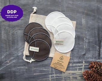 May include: A set of reusable round facial pads in white and dark gray, featuring a small tag labeled Plantish. The pads are accompanied by a beige mesh drawstring bag and a square brown paper card with the text Plantish Reusable Cotton Rounds.