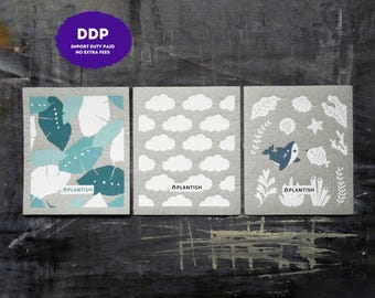 May include: Three square cellulose cleaning cloths featuring the brand name PLANTISH. The first cloth has a teal and white tropical leaf pattern. The second cloth has a white cloud pattern. The third cloth has a white marine life pattern.