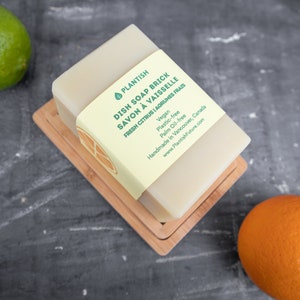 Pode incluir: Uma barra de sab&atilde;o para lavar lou&ccedil;a PLANTISH em um prato de madeira. O sab&atilde;o &eacute; etiquetado como "DISH SOAP BRICK SAVON &Agrave; VAISSELLE FRESH CITRUS | AGRUMES FRAIS" e lista os ingredientes como veganos, livres de pl&aacute;stico e livres de &oacute;leo de palma. O sab&atilde;o &eacute; feito &agrave; m&atilde;o em Vancouver, Canad&aacute;. O r&oacute;tulo tamb&eacute;m inclui o endere&ccedil;o do site: www.PlantishFuture.com.