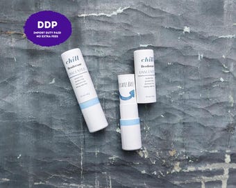 Peut inclure: Deux bâtons de déodorant cylindriques blancs avec des accents bleu clair et du texte noir indiquant chill Deodorant UNSCENTED. Un bâton est fermé, tandis que l'autre est ouvert, montrant une base rotative avec une flèche et le texte ROTATE BASE.