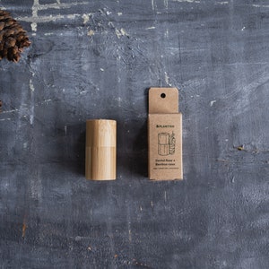 May include: A cylindrical bamboo dental floss case and its matching brown cardboard packaging box. The box features the Plantish logo, a line drawing of the floss container, and the text Dental floss + Bamboo case, vegan, plastic-free, plant-based.