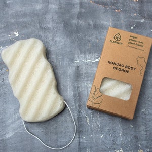 May include: A white konjac body sponge in a brown cardboard box with the text "PLANTISH vegan plastic-free plant-based PlantishStore.com KONJAC BODY SPONGE" printed on it.
