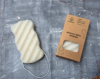 May include: A white konjac body sponge in a brown cardboard box with the text "PLANTISH vegan plastic-free plant-based PlantishStore.com KONJAC BODY SPONGE" printed on it.