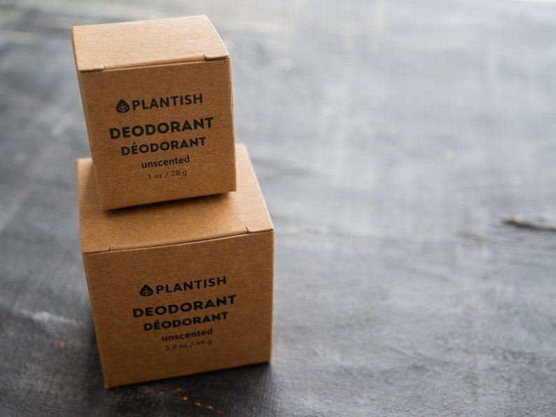 Puede incluir: Dos cajas de cart&oacute;n marr&oacute;n apiladas de desodorante sin aroma Plantish. La caja superior est&aacute; etiquetada con 1 oz / 28 g y la inferior con 3,5 oz / 99 g. Ambas cajas presentan texto negro y un logotipo de hoja en la parte frontal.