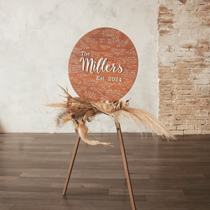Brown wooden easel for wedding round alternative guest book with personalization and other decor in rustic or boho style