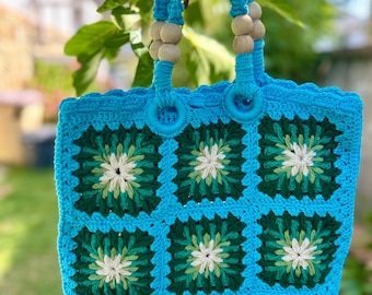 May include: A handmade turquoise crochet tote bag with a floral pattern in green and white. The bag has wooden bead accents on the handles and the text "http://catherinemacrame.etsy.com" is visible.