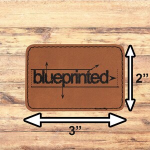 May include: A brown leather patch with the word "blueprinted" in black text. The patch is 3 inches wide and 2 inches tall.