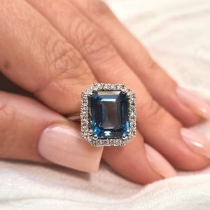 Exclusivo anillo de oro blanco de 14 k con topacio azul Londres y halo de diamantes llamativos