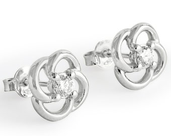 Puede incluir: Un par de pendientes de plata con un pequeño diamante en el centro de cada pendiente. Los pendientes tienen forma de flor con cuatro pétalos.