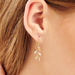 May include: Gold earrings with a delicate branch design featuring small sparkling diamonds.