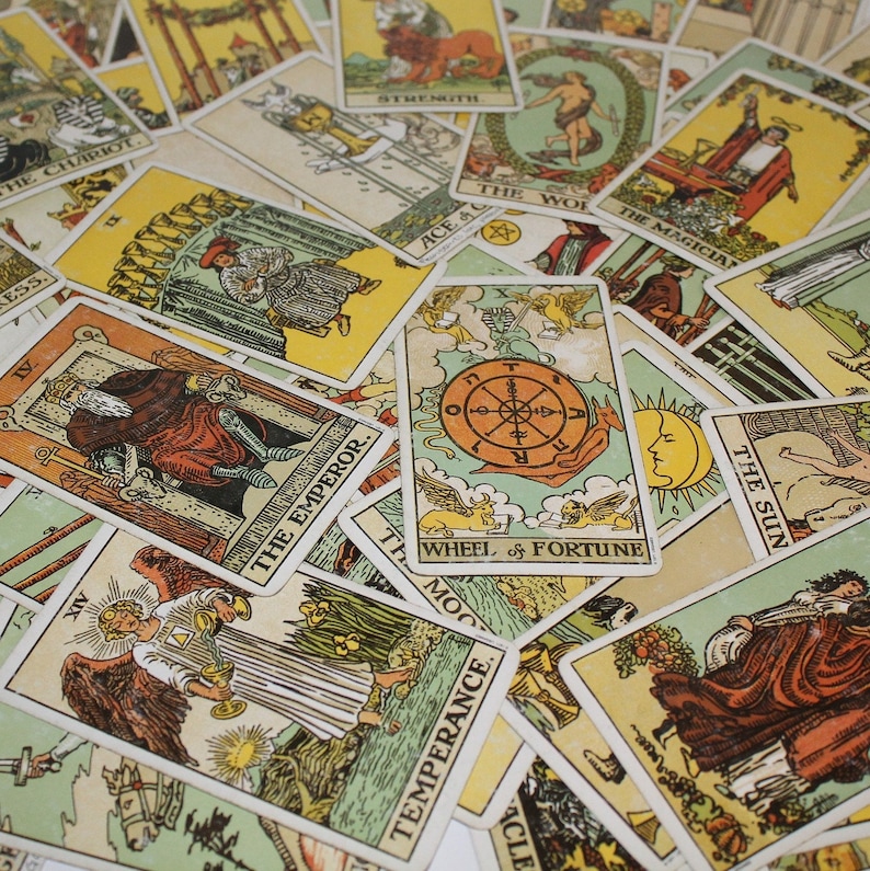 Op de afbeelding: Een verzameling tarotkaarten met diverse illustraties en titels. De kaarten tonen afbeeldingen van De Keizer, De Zon, Het Rad van Fortuin en andere Grote Arcana kaarten. Het kleurenpalet omvat geel, oranje en bruin.