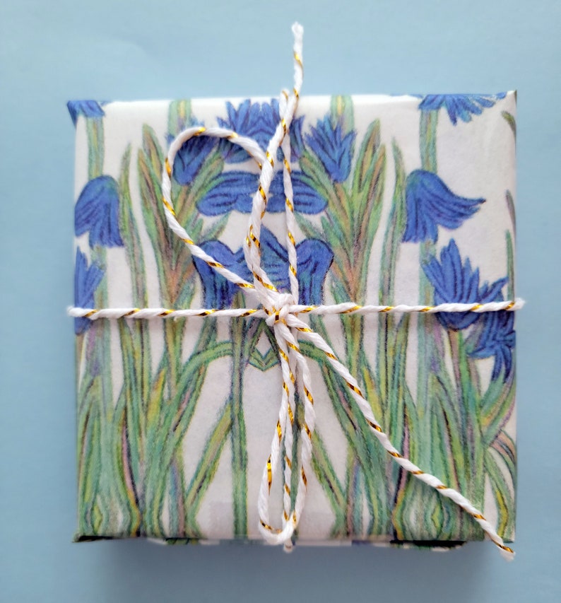 Shown above: A small gift box wrapped in the paper. The box is tied with white twine with a gold thread running through it.
