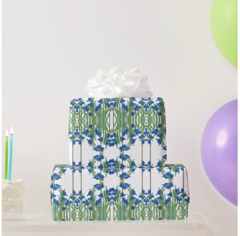 Shown above: a large rectangular gift box and a smaller square medium sized gift box, both wrapped in the paper. The boxes are stacked on top of each other and topped with a white bow (not included). There is a birthday cake with candles on the far right and two balloons on the far left.